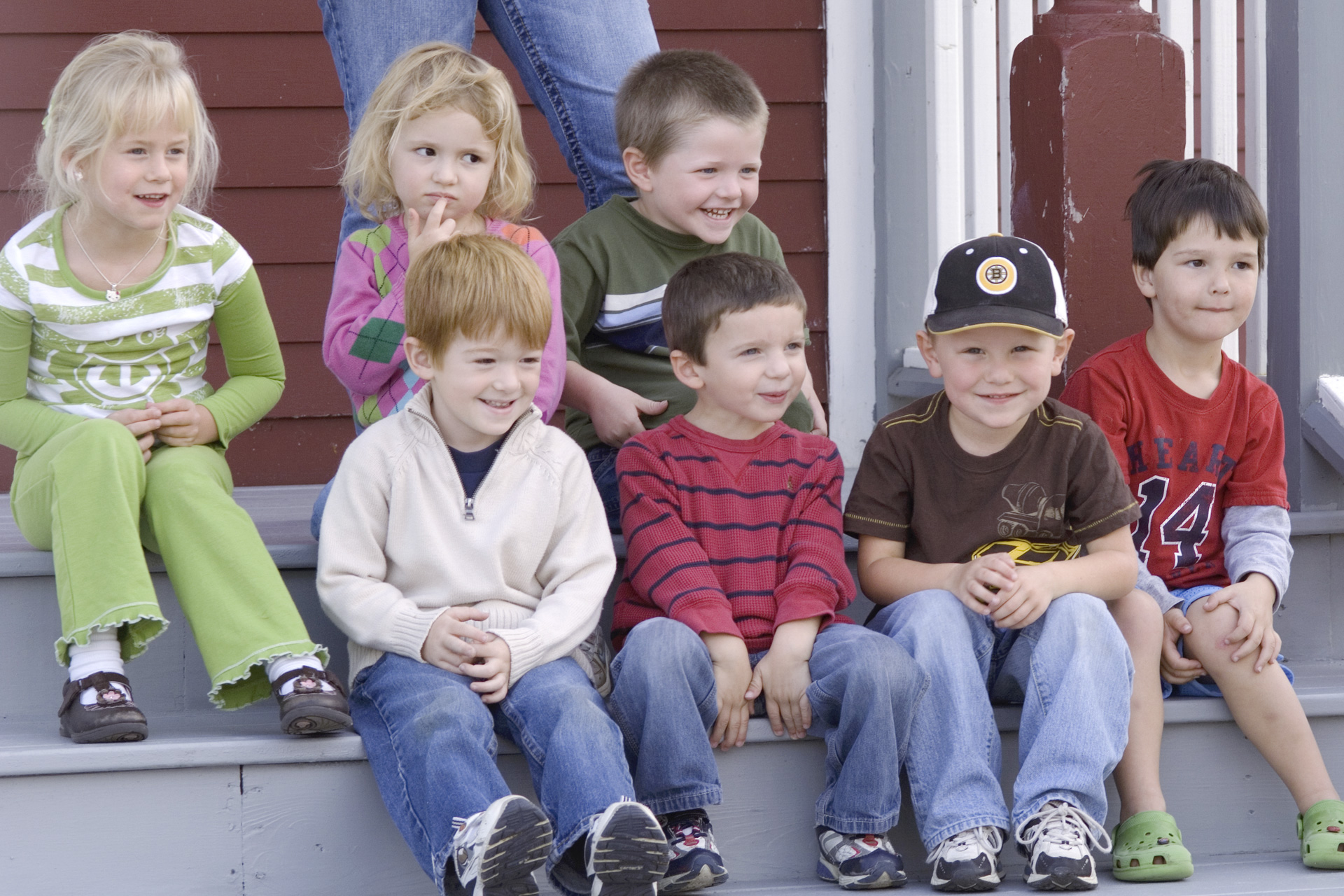 A small group of children sit on the stairs of their school