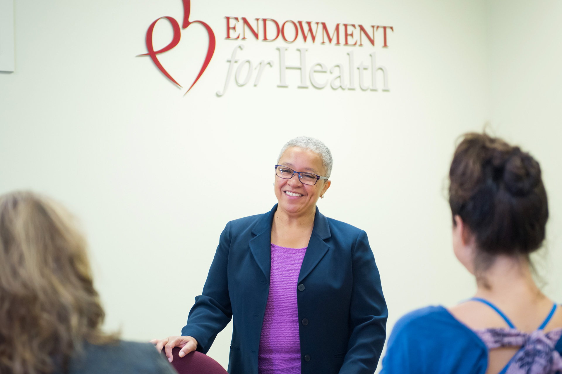 Woman speaks to visitors with Endowment for Health logo behind her