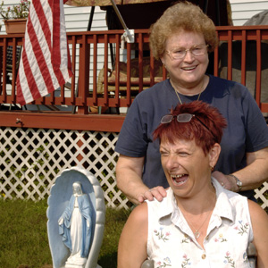 Two woman stand on the lawn outside a manufactured home