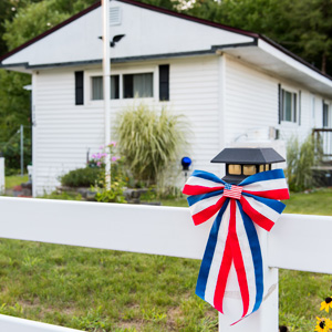 Red, white, and blue ribbon tied to a post in front of a new manufactured home