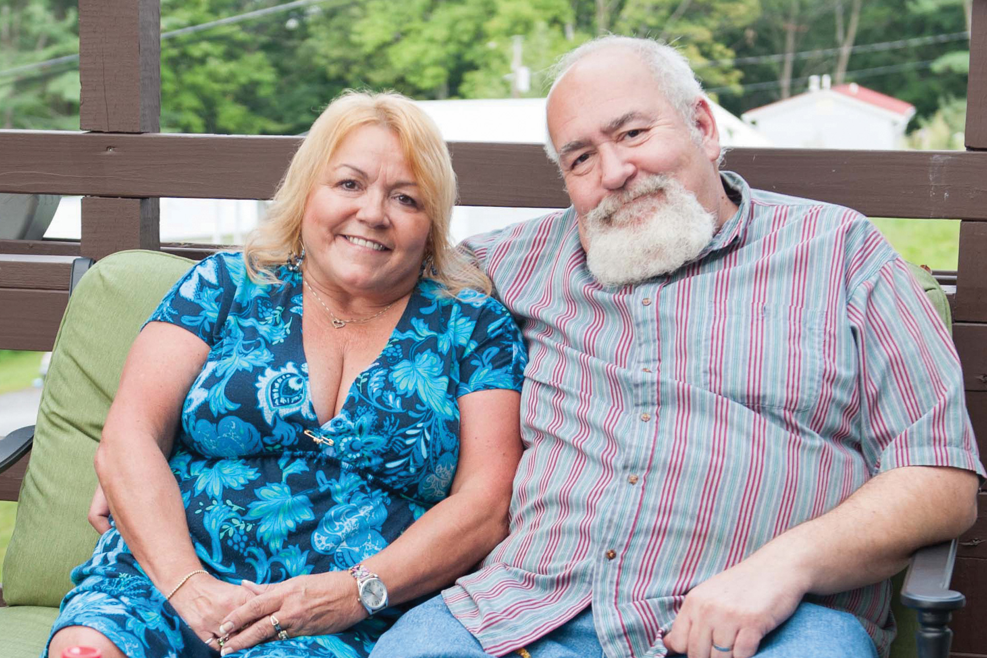 Middle-age couple sit on a loveseat on their deck