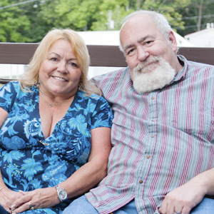 Middle-age couple sit on a loveseat on their deck