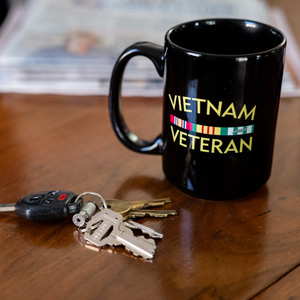 A veterans coffee cup and house keys say "welcome home."